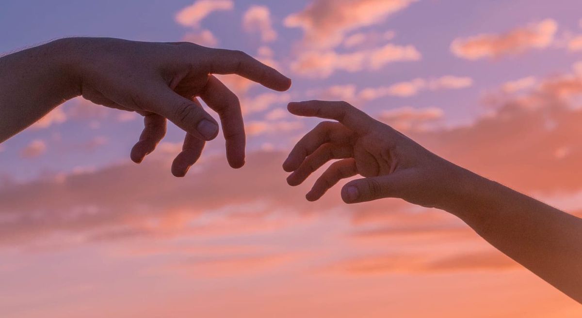 Two hands in front of sunset skyline